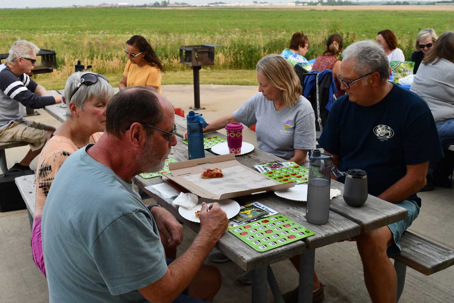 People sitting outdoors at picnic tables playing bingo.