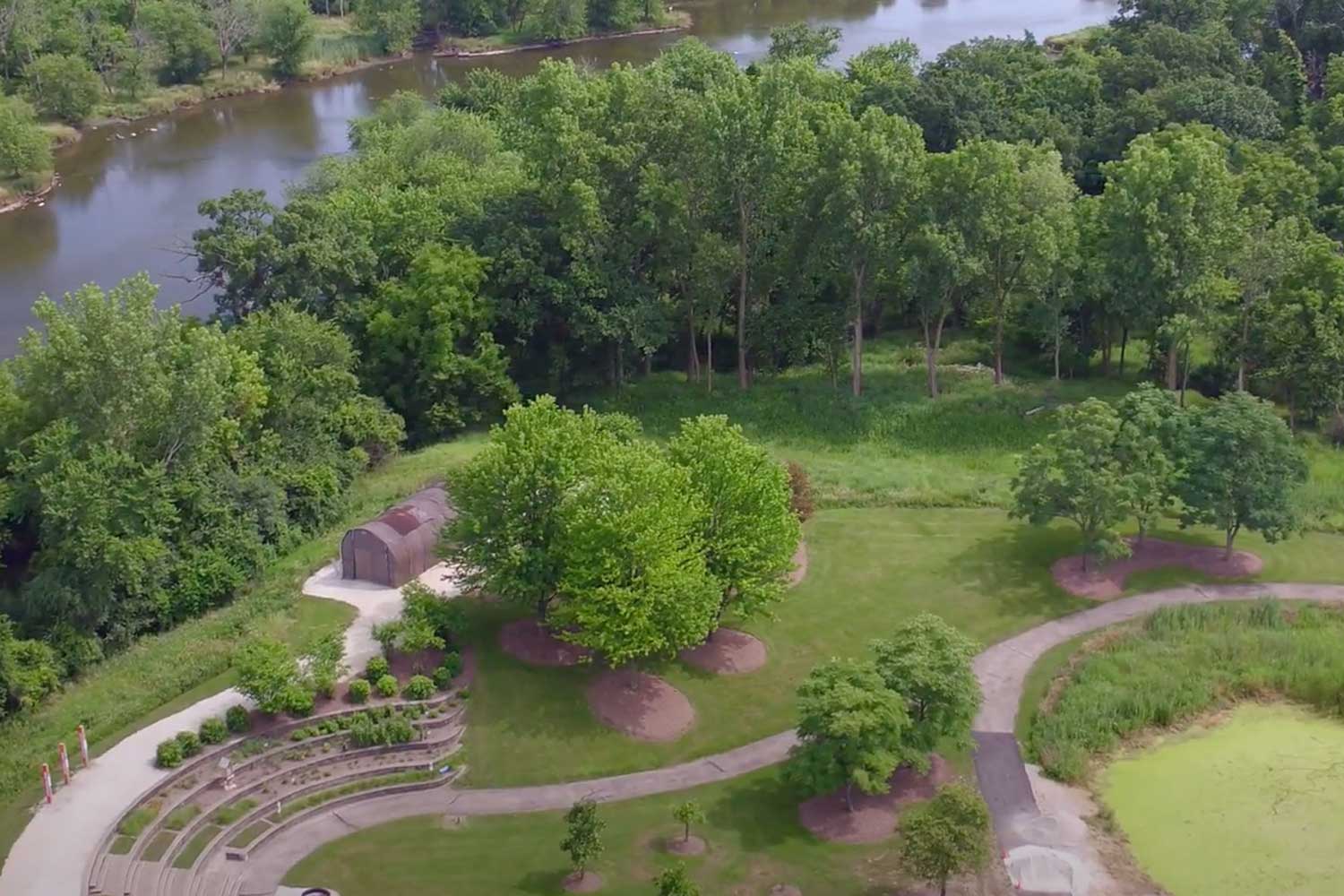 An aerial photo of the grounds of Isle a la Cache with a river in the background and trails cutting through the grass.