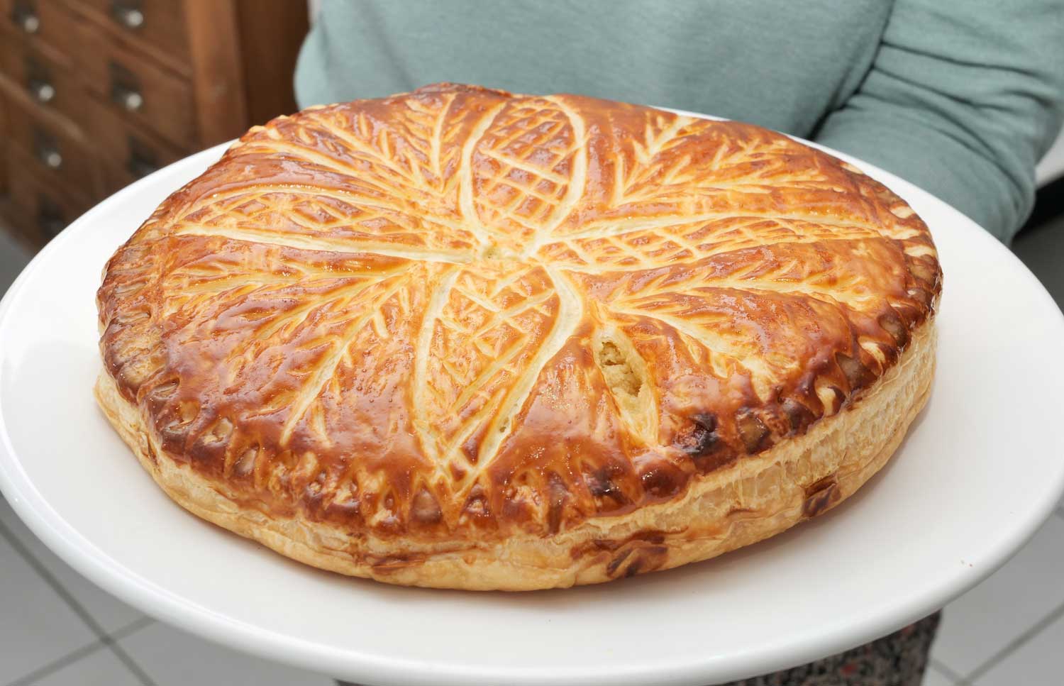 A person holding a king cake on a large white platter.