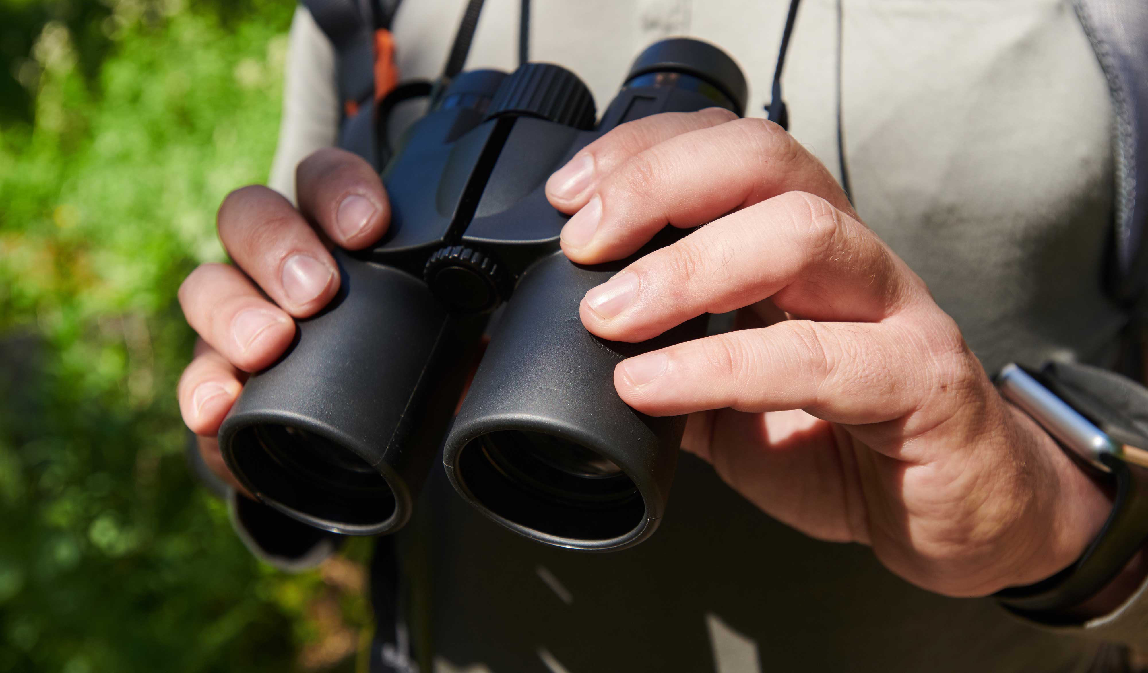 Close-up of a person holding binoculars. 