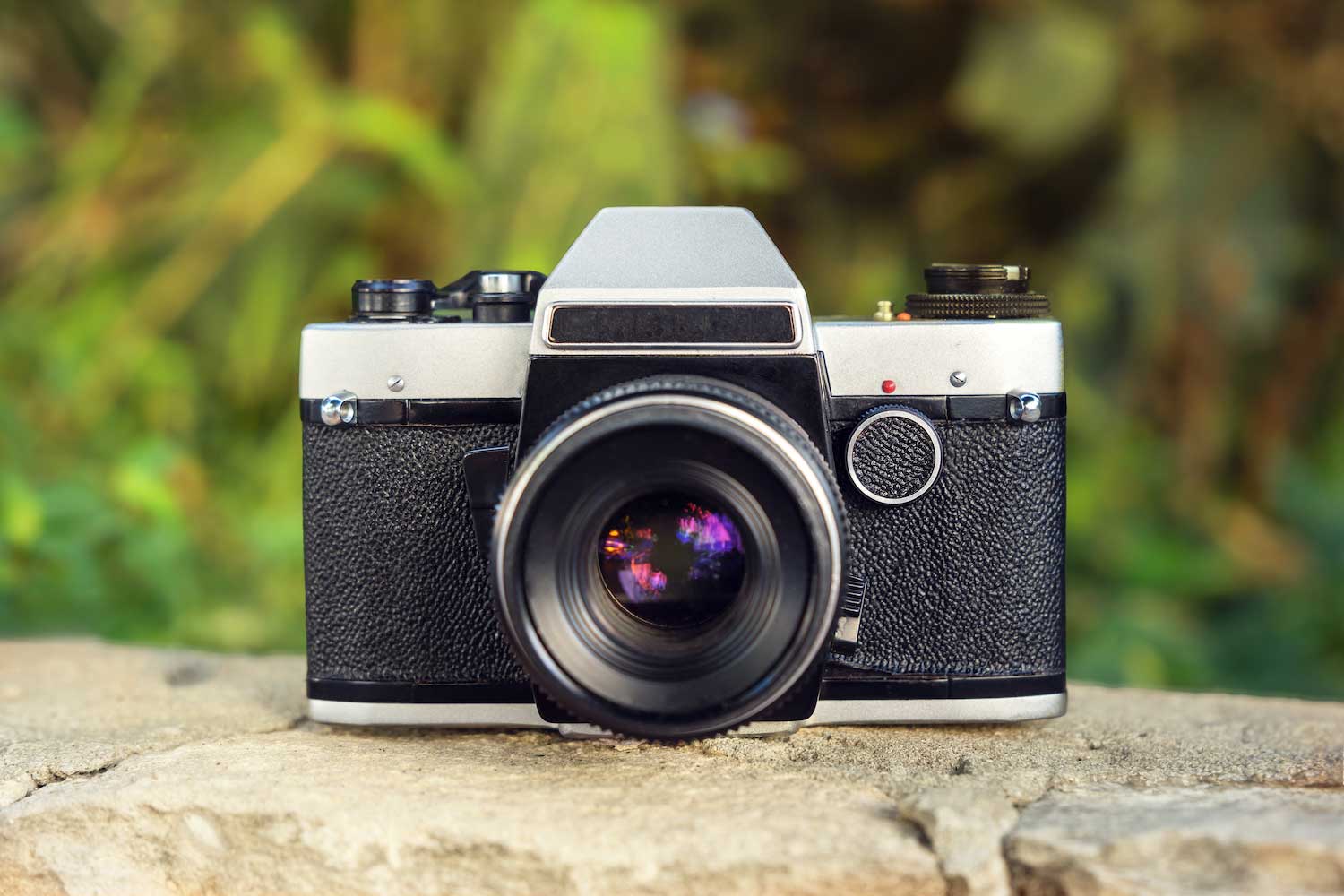 A retro camera resting on a stone ledge.