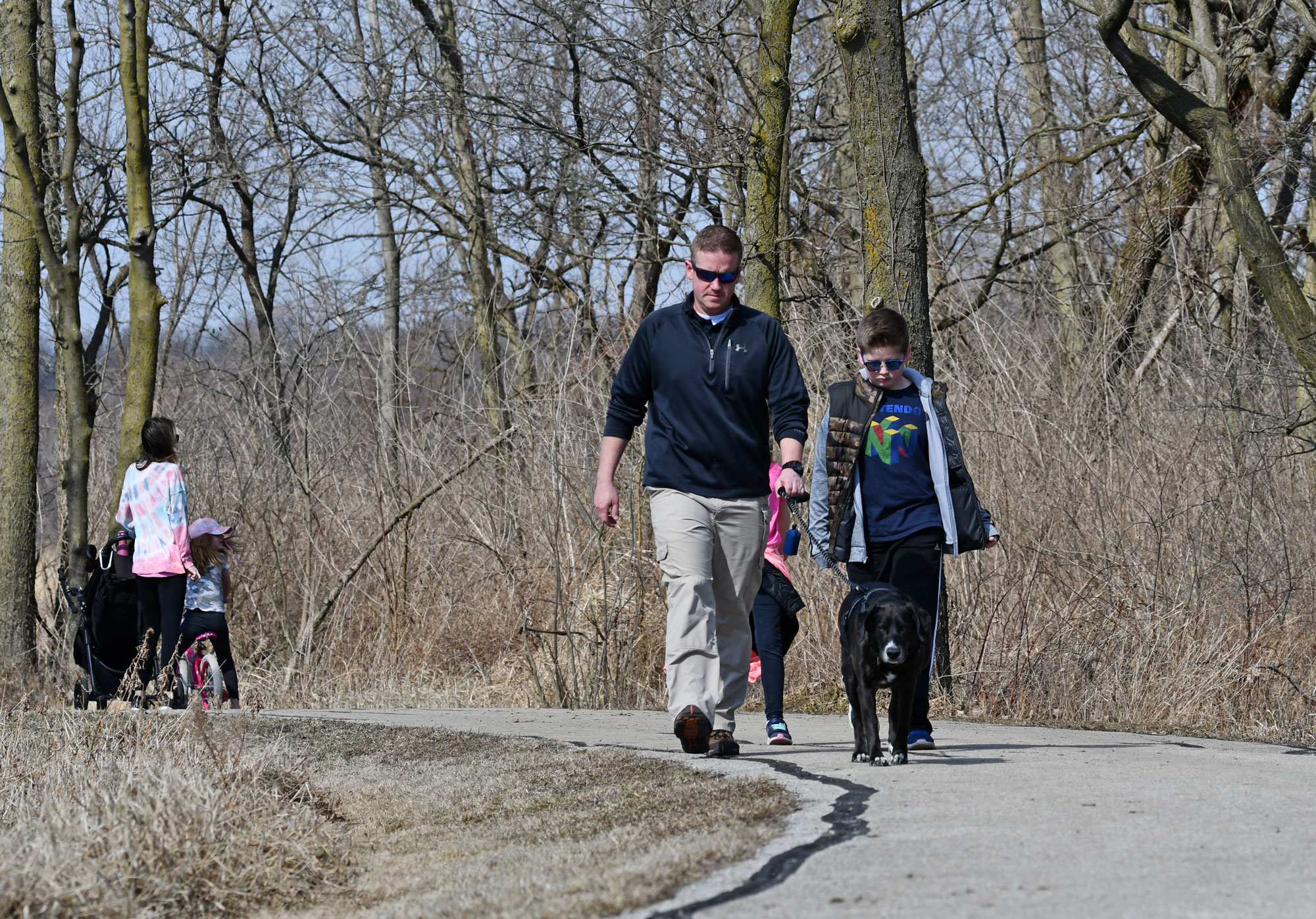 People walk on a paved trail.