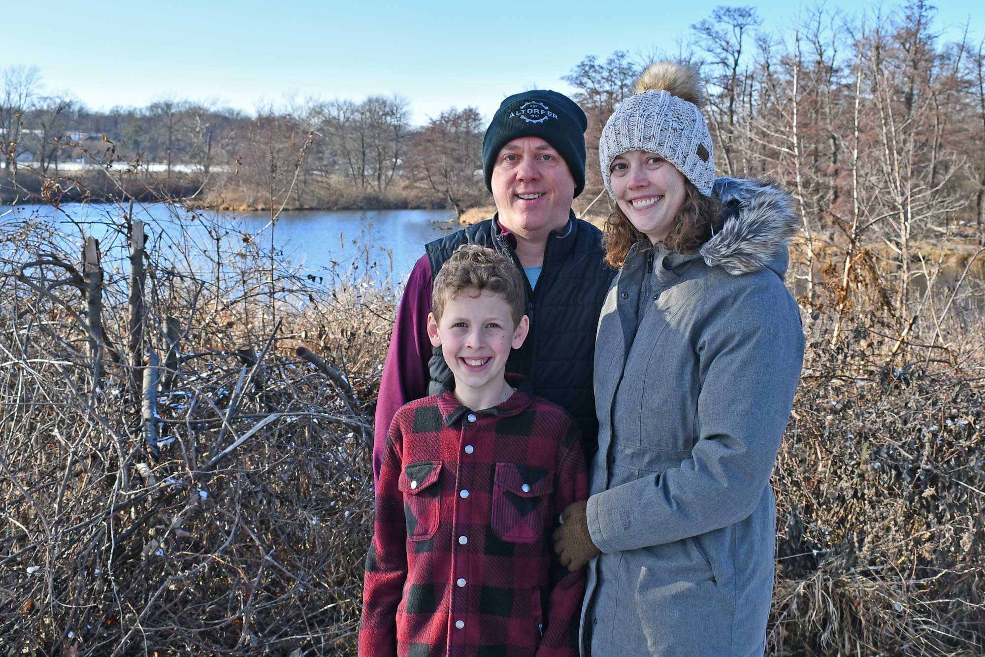 A family stands for a portrait by a river.