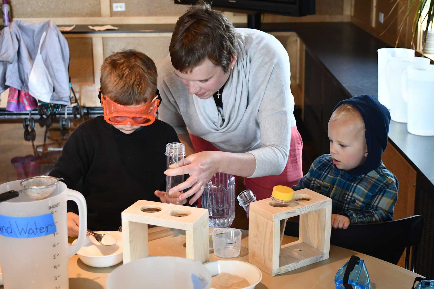 An adult and two kids at a table working on a science experiment