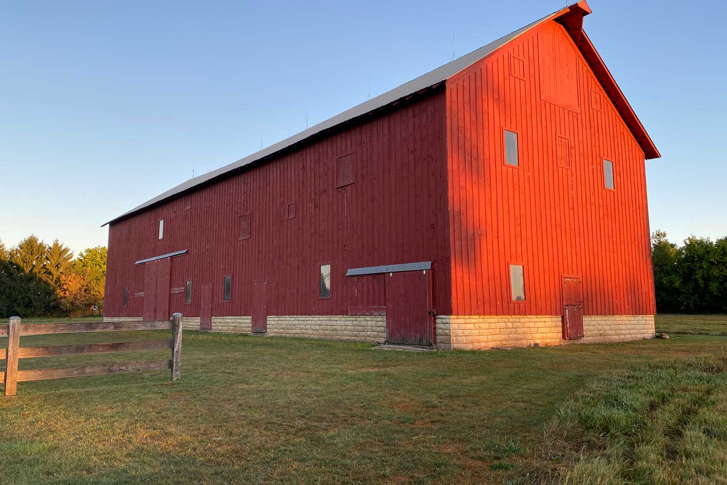 A large red barn in the glow of the setting sun.