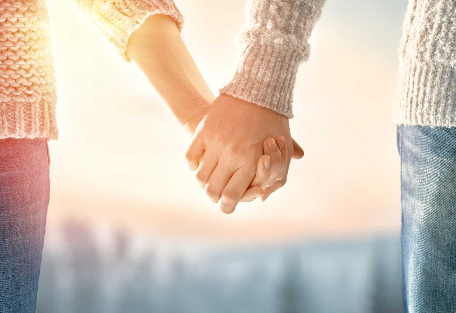 A closeup of two people holding hands outside.