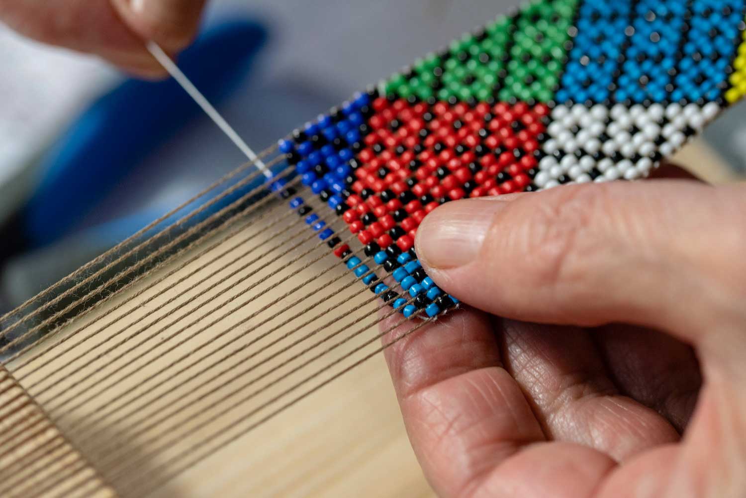 A closeup showing someone beading by hand.