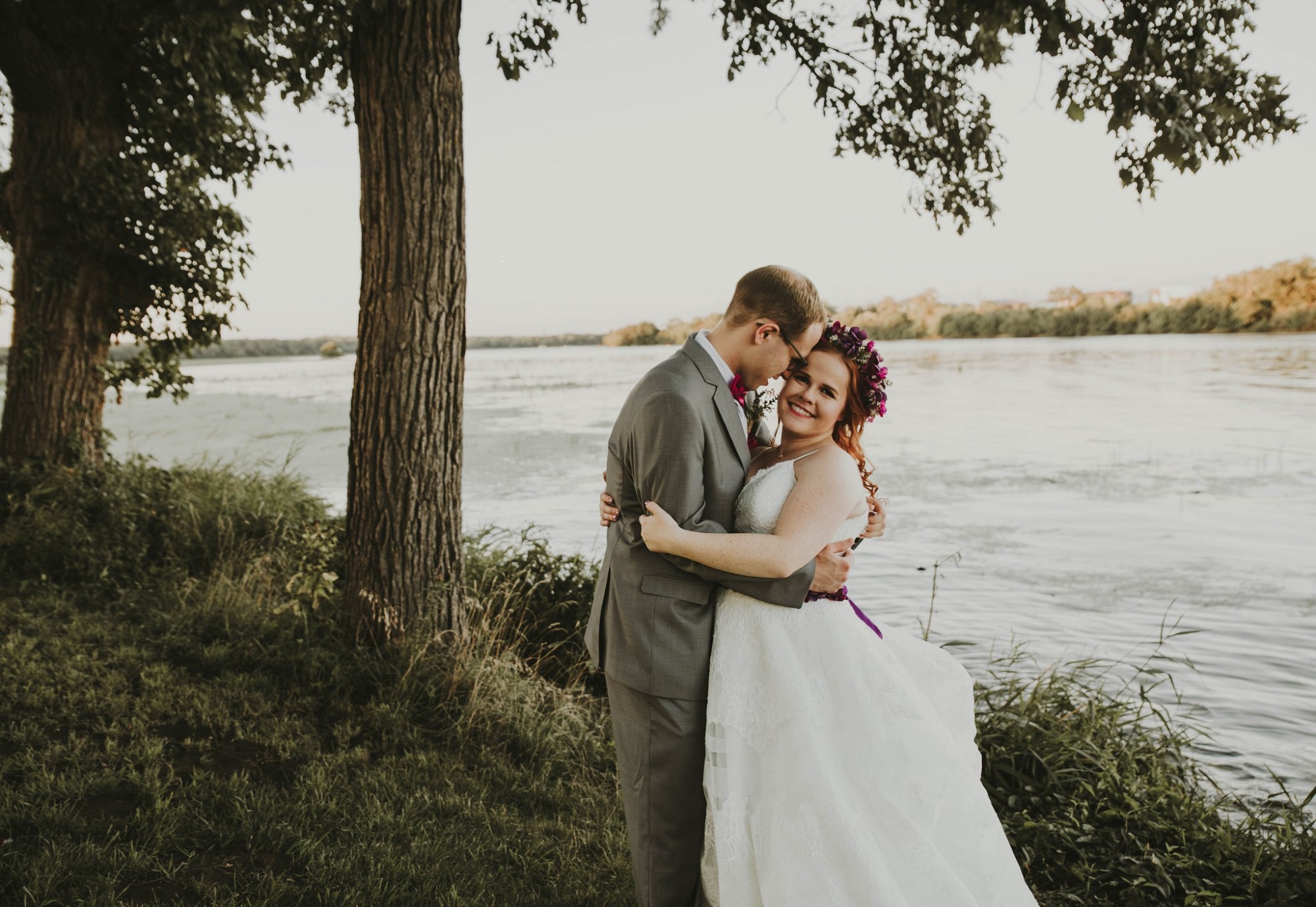 A wedding couple embracing by a river.