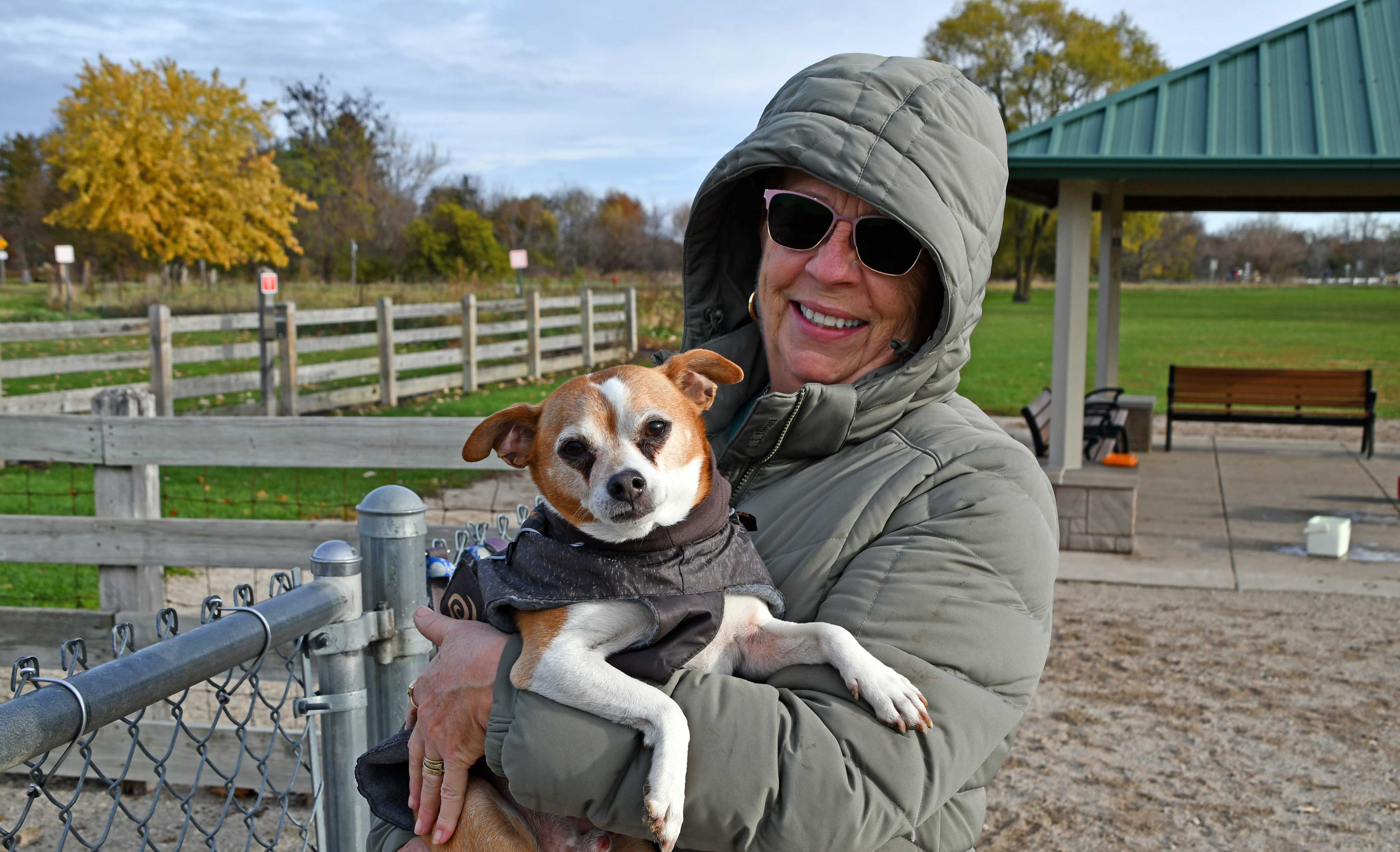 A dog park user holding a dog.