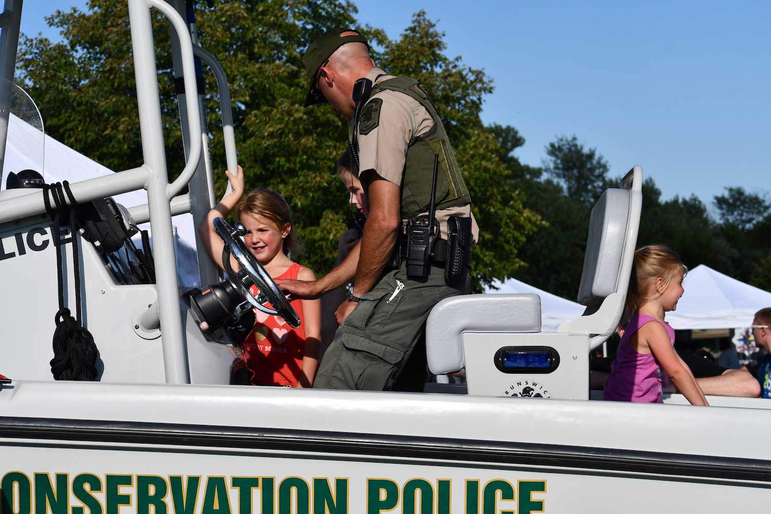 A conservation police officer showing kids a police boat.