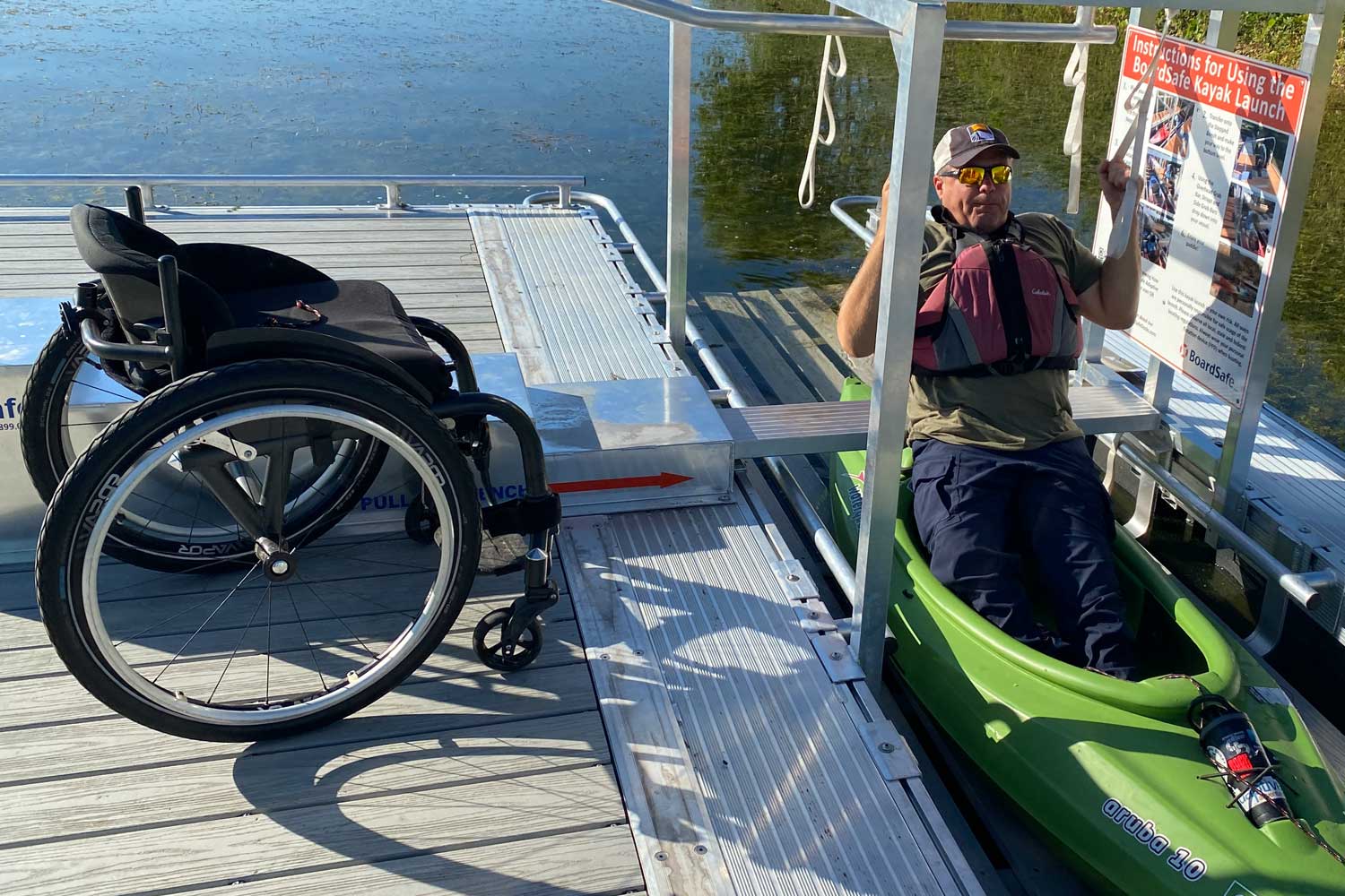 Person getting into a kayak while using an assisted kayak launch.