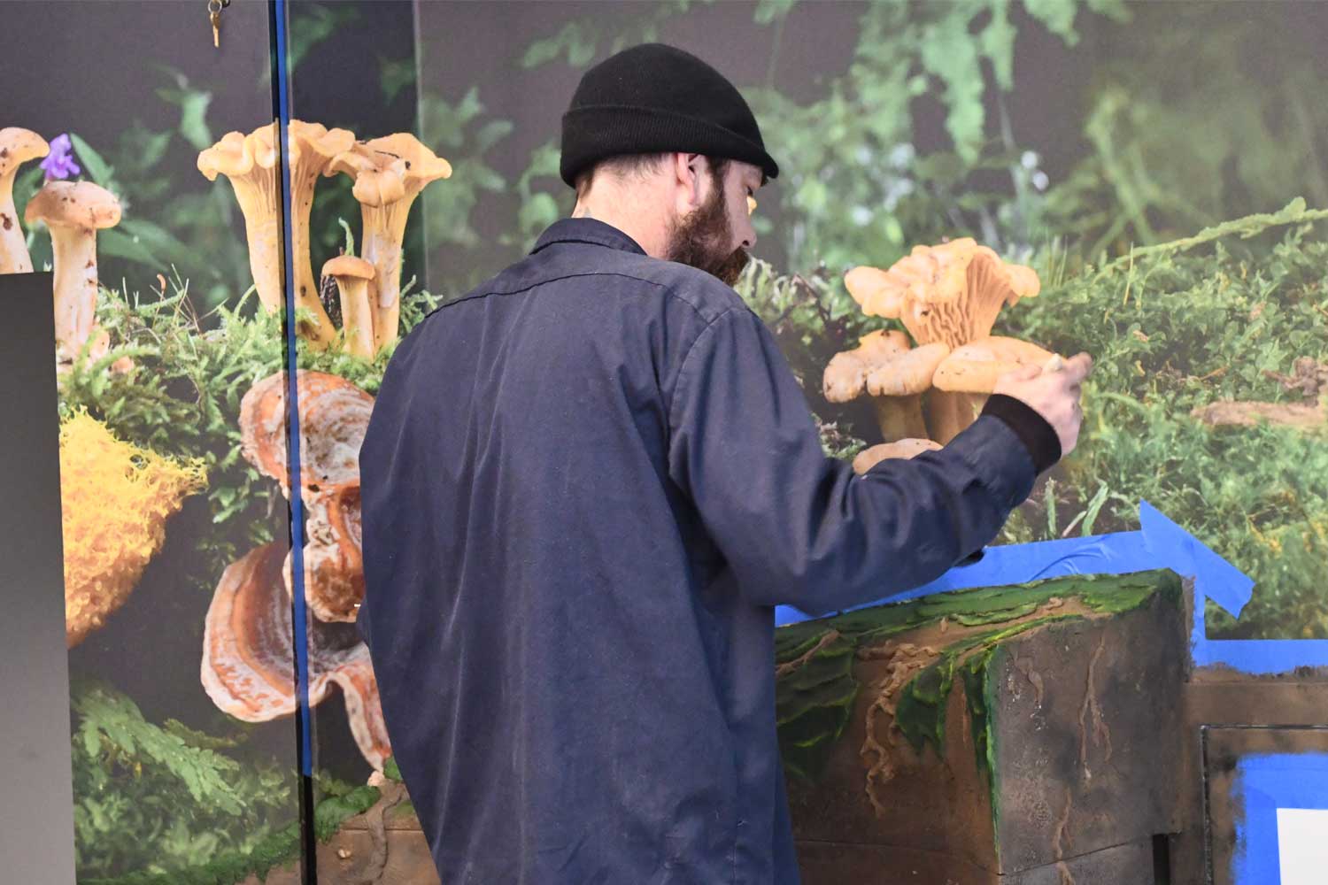 Worker painting interactive exhibit in a nature center.