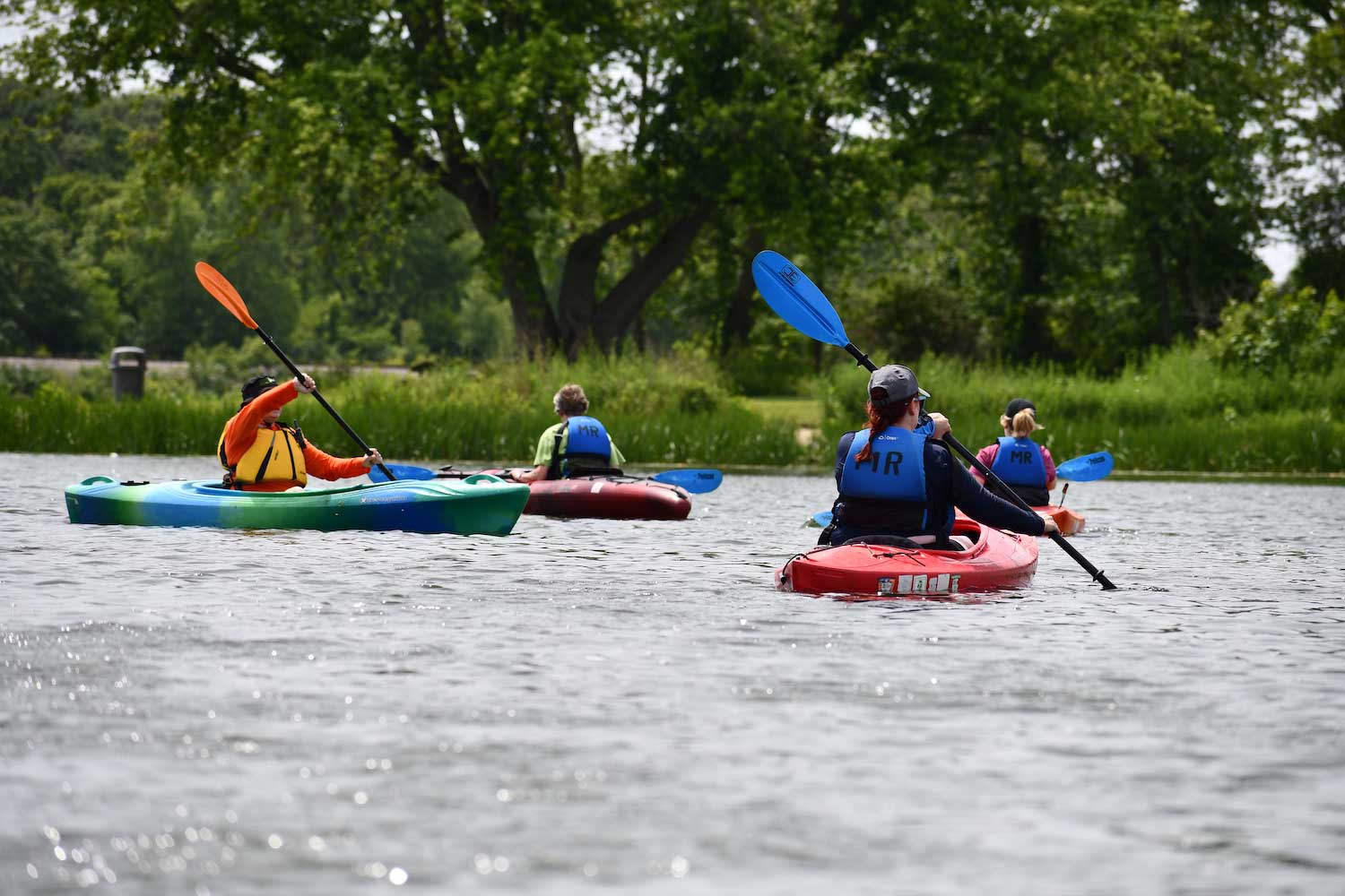 A group of people in kayaks on a lake during an instruction paddling program.