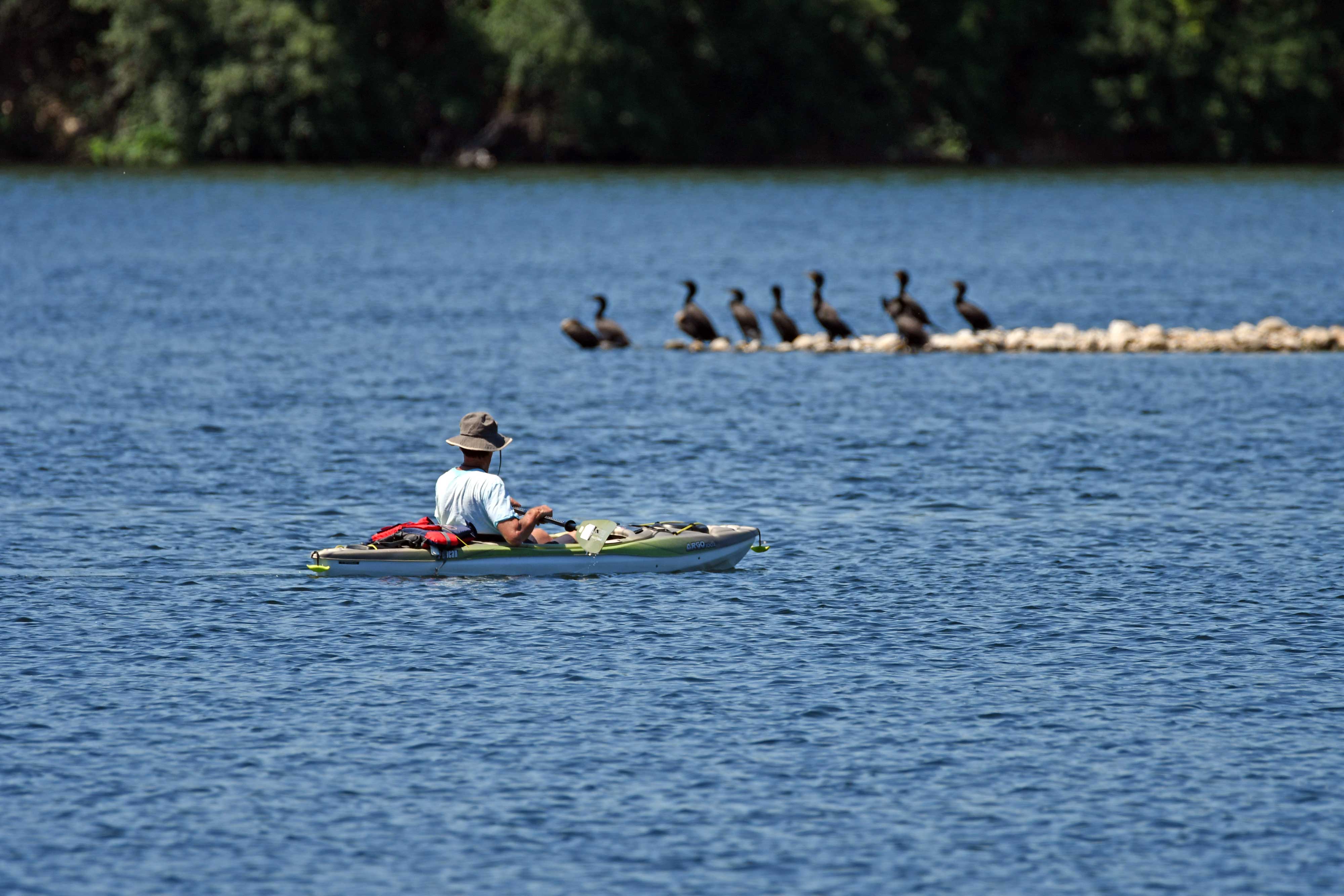 A person on a kayak in clear blue water.