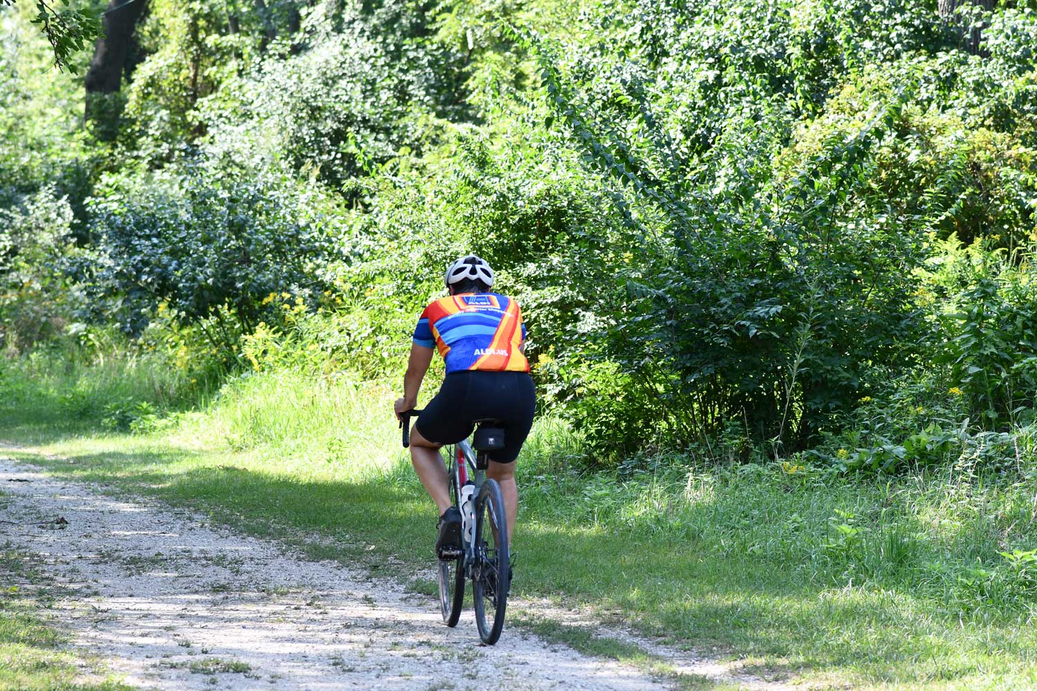 A person riding a bike on a crushed limestone trail.