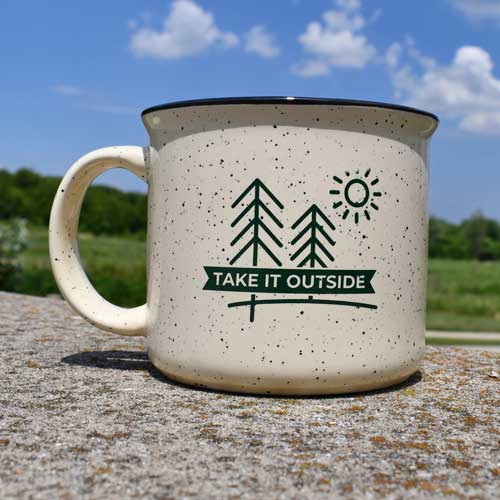 A coffee mug with a take it outside logo on it
