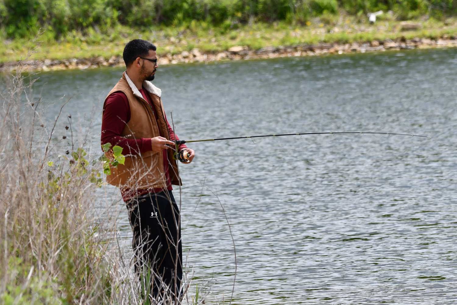 Person fishing with water in the background.
