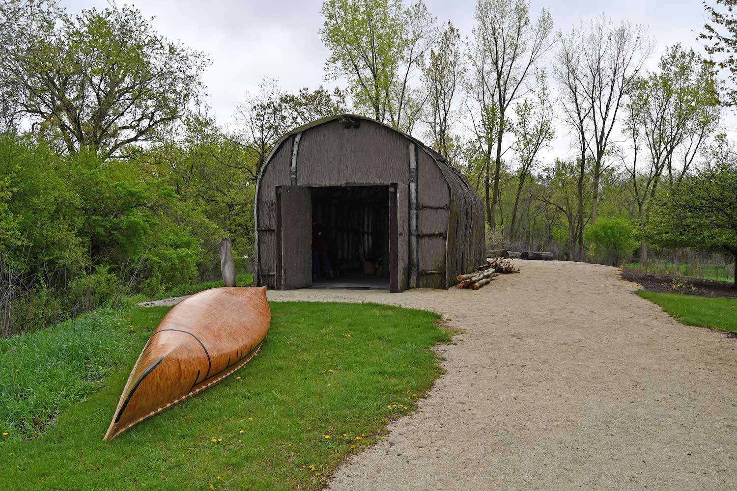 A Native American longhouse and a wooden canoe.