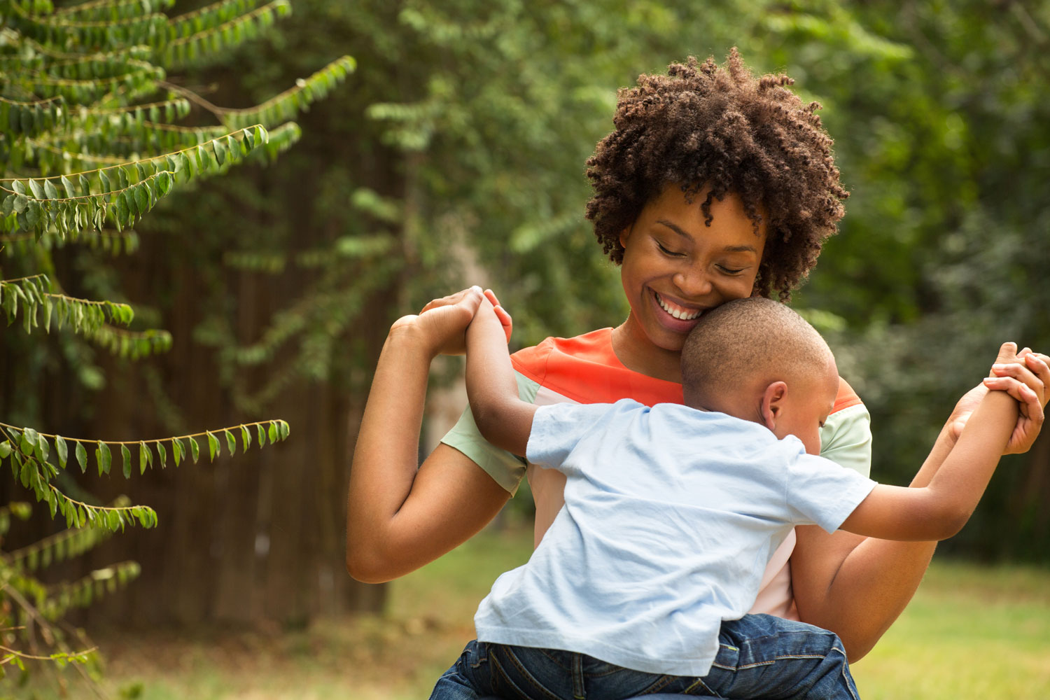 A woman hugging a young child while sitting on the grass