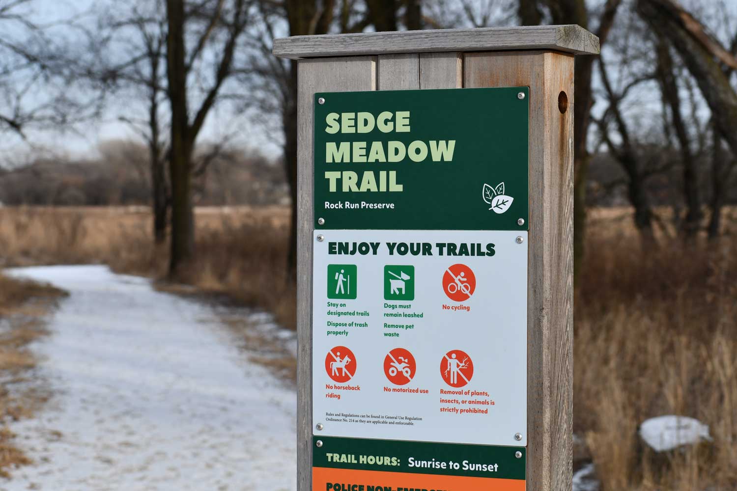 Trailhead sign with snowy trail in background