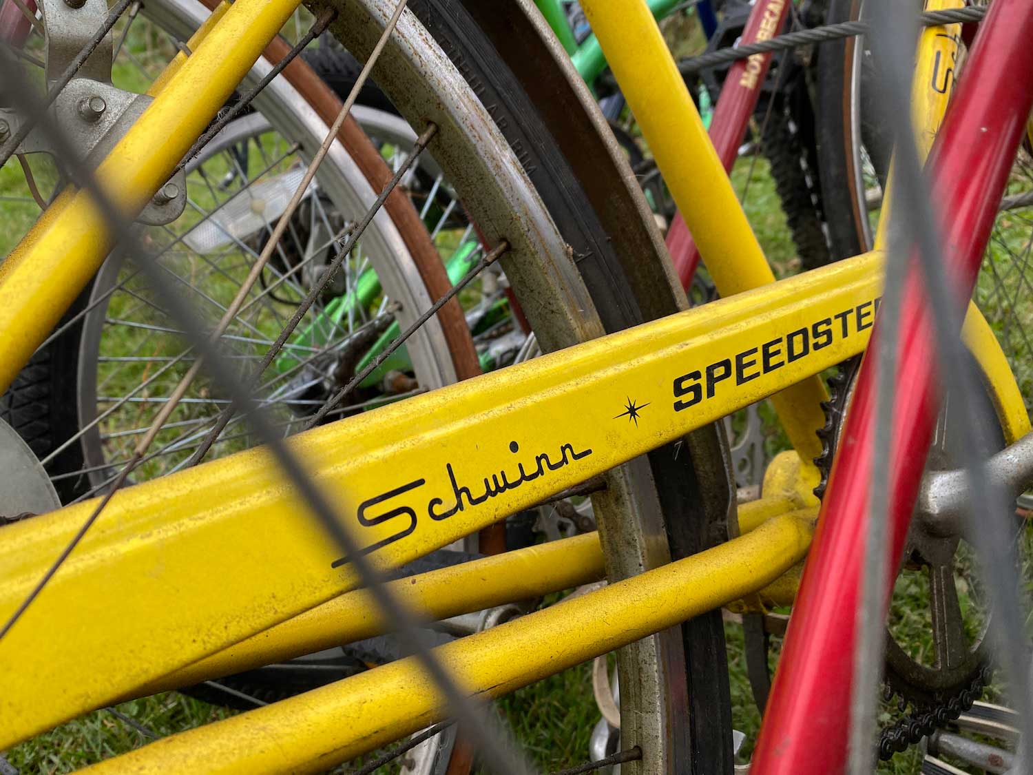 The closeup details of the frame of a yellow Schwinn bicycle.