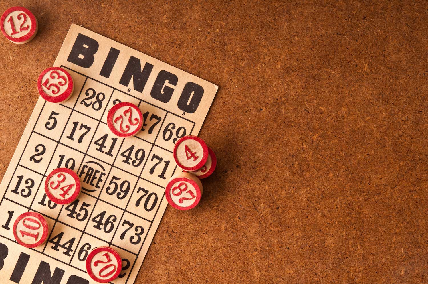 A bingo card and bingo balls on a wooden surface.