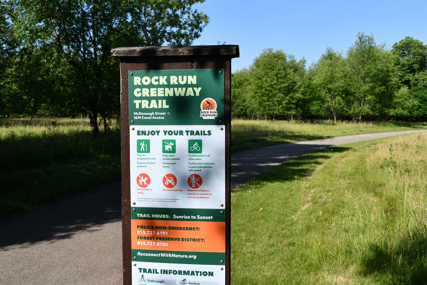 Trail sign in front of a paved trail.