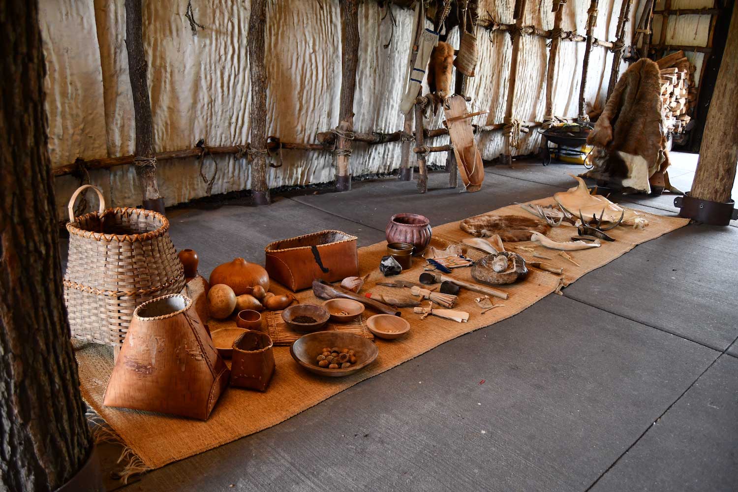 Artifacts laid out on the floor of a Native American longhouse.