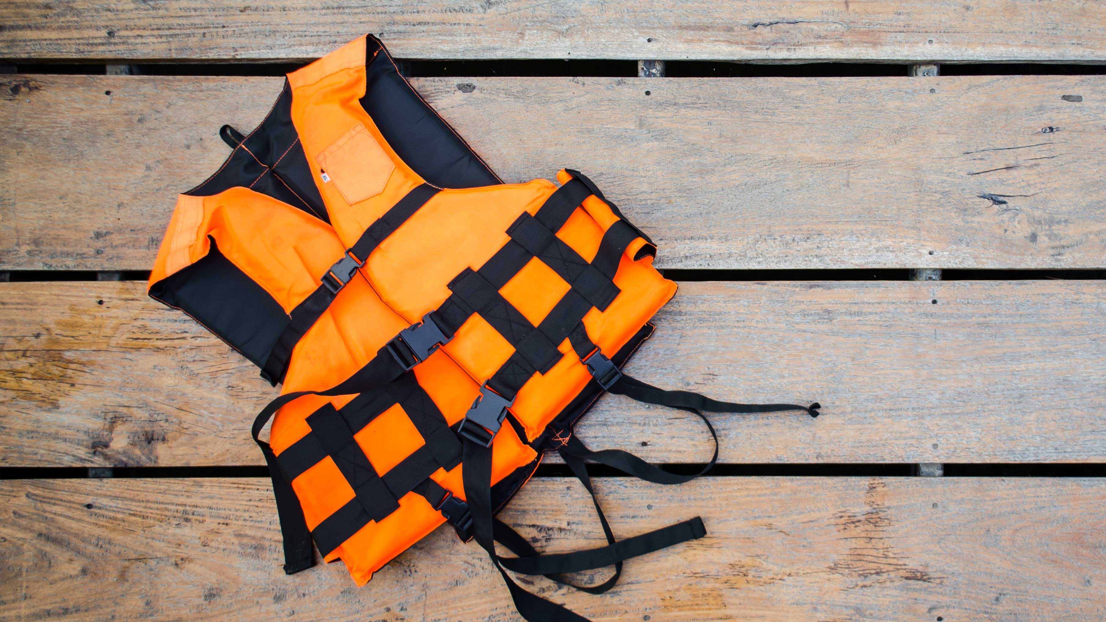 A life jacket laying on a wooden surface.