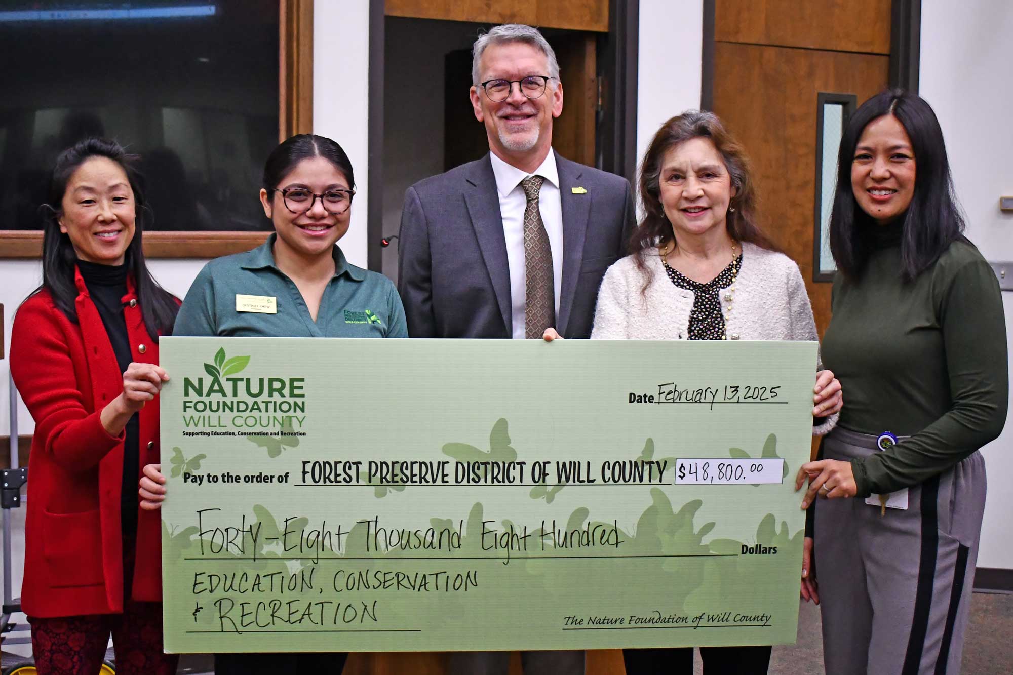 Board members pose with a large check. 