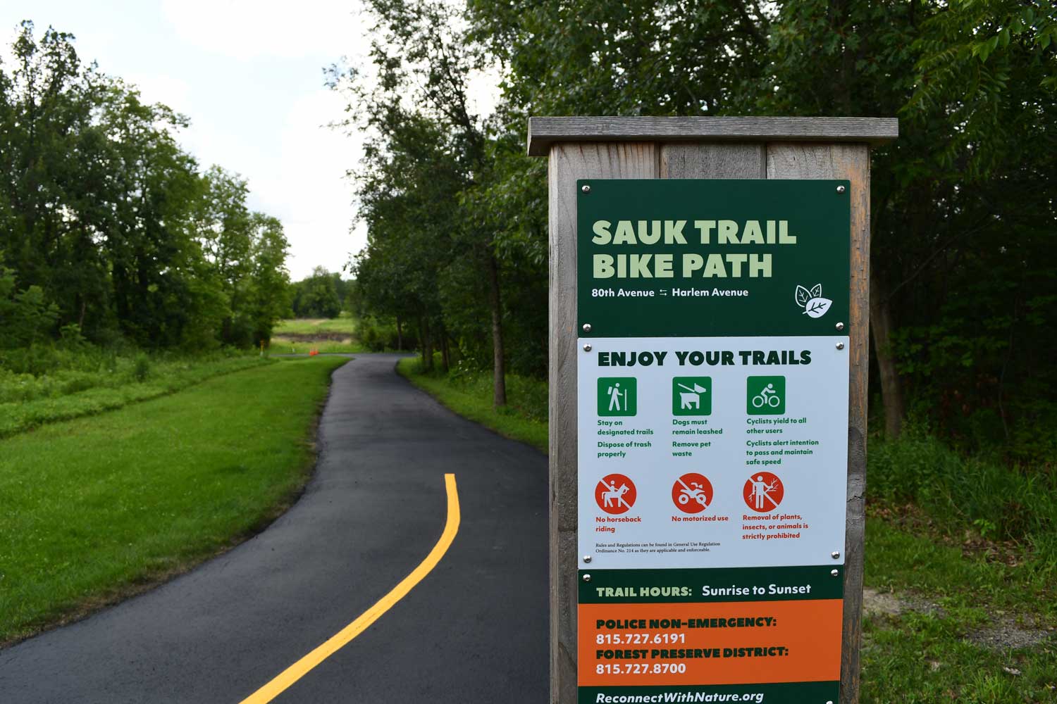 Trail sign in front of a paved trail.